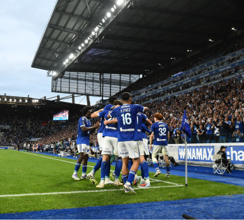 Soccer team celebrating goal near corner flag stadium